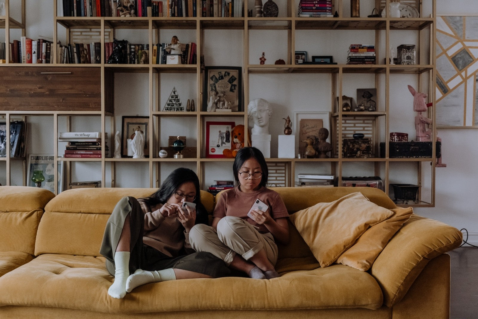 Two girls having a chill time with their mobile phones on a sofa chair at rooms for rent at Springville Residence Taman Equine Park